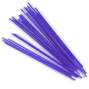 Könnte beinhalten: Ein Bündel dünner, violetter Glasstäbe, etwa 30 cm lang, die zum Glasblasen verwendet werden.