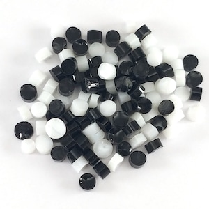 May include: A pile of black and white round glass beads. The beads are small and have a smooth, glossy finish.