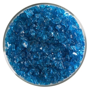 May include: A close-up view of a bowl filled with small, turquoise blue glass pieces. The glass pieces are irregular in shape and have a slightly frosted appearance.