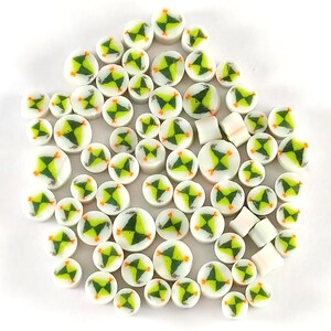 May include: A collection of white ceramic tiles with a green and orange geometric design. The tiles are round and have a glossy finish.