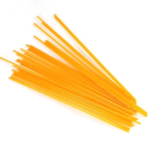May include: A pile of uncooked spaghetti noodles. The pasta is a bright yellow-orange color and is arranged in a diagonal pattern against a white background. The noodles are long and thin, typical of spaghetti.