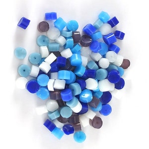 May include: A large pile of small, round, glass beads in shades of blue, white, and purple. The beads are arranged in a random pattern.