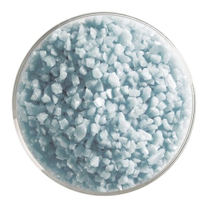 May include: A close-up view of a glass bowl filled with light blue bath salts. The salts are small and irregular in shape, creating a textured surface.
