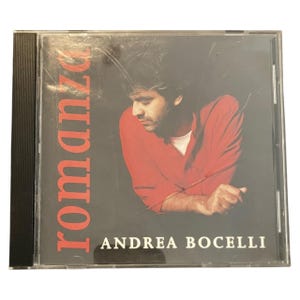 May include: A CD case featuring Andrea Bocelli's album "Romanza." The cover art shows Bocelli in a red shirt against a dark background. The album title is in large, red letters, and the artist's name is in white.