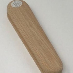 Op de afbeelding: Een houten, lichtbruine, ovale schoenspanner met een rond label aan de bovenkant met de tekst "Shoe Stretcher".