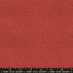 Puede incluir: Primer plano de una tela de lino roja con una textura tejida sutil. La tela se muestra con una regla para la escala.