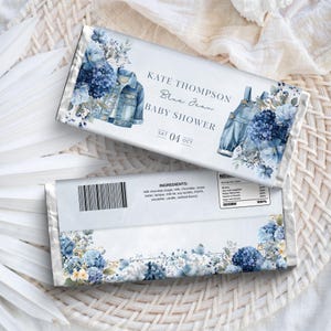 May include: Two chocolate bar wrappers with a baby shower theme. The wrappers feature watercolor illustrations of a denim jacket and overalls, along with blue floral accents. Text reads "KATE THOMPSON Blue Jean BABY SHOWER SAT 04 OCT."