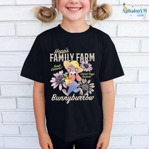 A young girl wearing a black t-shirt with a cartoon rabbit and text related to a farm.