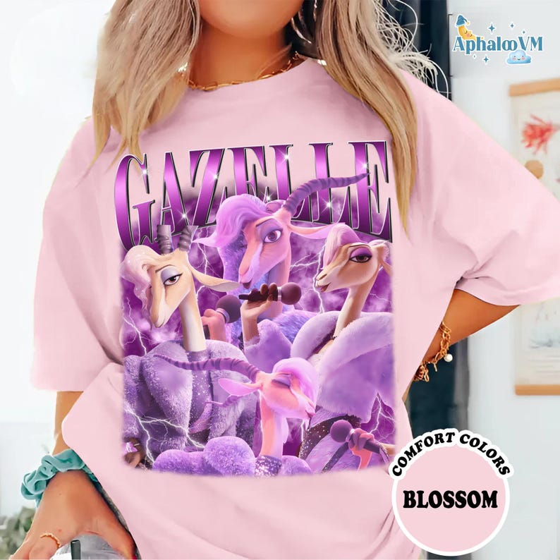 A woman wearing a pink t-shirt with a graphic design featuring purple and pink cartoon animals, including a unicorn and a dragon, along with the text "Gazelle" and "Blossom".