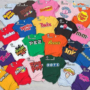 May include: A collection of colorful t-shirts, each featuring a different candy brand logo. The shirts are in various colors, including light blue, pink, red, and green. The brands include Starburst, Twix, and Reese's.
