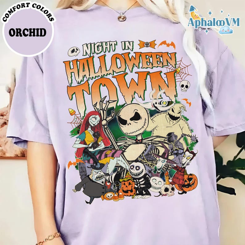 May include: An orchid-colored t-shirt featuring a graphic print with the text "NIGHT IN HALLOWEEN TOWN" in orange and green. The design includes various characters from The Nightmare Before Christmas, including Jack Skellington, Sally, and Oogie Boogie, surrounded by pumpkins, spiderwebs, and bats.