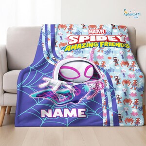 May include: A Spidey and His Amazing Friends blanket featuring a large graphic of Spider-Gwen in a web design. The blanket has a light blue background with repeating spider and character designs. The word "NAME" is displayed.