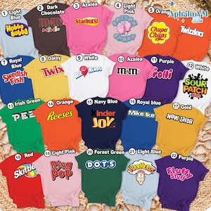 May include: A collection of colorful t-shirts, each featuring a different candy brand logo. The shirts come in various colors, including light blue, pink, orange, and green. The text on the shirts includes brands like Starburst, Twix, and Reese's.
