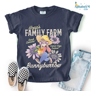 a dark blue t-shirt with a cartoon rabbit holding a basket of carrots, surrounded by flowers, and the text "Hopp's FAMILY FARM" and "Bunnyburrow" printed on it. The t-shirt is placed on a white background, with a pair of black and white checkered shoes and a pair of blue jeans visible next to it.