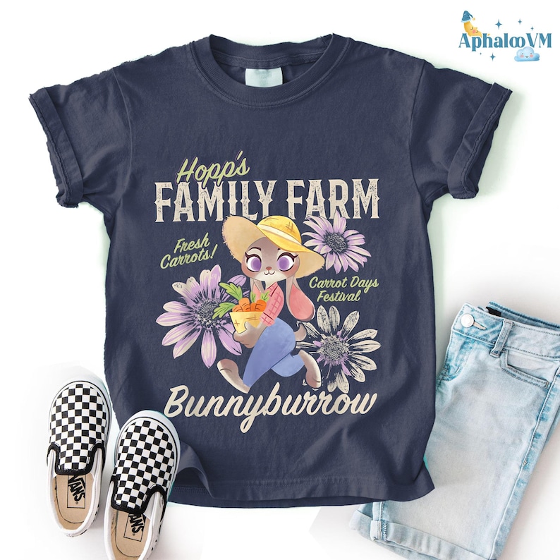 a dark blue t-shirt with a cartoon rabbit holding a basket of carrots, surrounded by flowers, and the text "Hopp's FAMILY FARM" and "Bunnyburrow" printed on it. The t-shirt is placed on a white background, with a pair of black and white checkered shoes and a pair of blue jeans visible next to it.