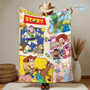 May include: A beige blanket with cartoon characters from "Toy Story." The blanket has a "Paisley Story" logo and features Buzz Lightyear, Woody, and other characters. The blanket is a fun and colorful item.