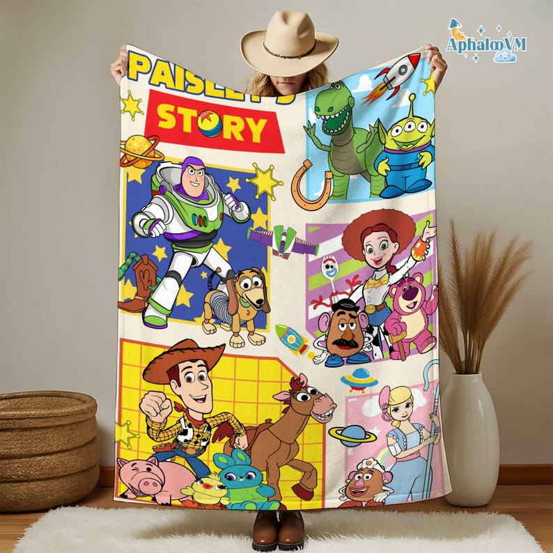 May include: A beige blanket with cartoon characters from "Toy Story." The blanket has a "Paisley Story" logo and features Buzz Lightyear, Woody, and other characters. The blanket is a fun and colorful item.