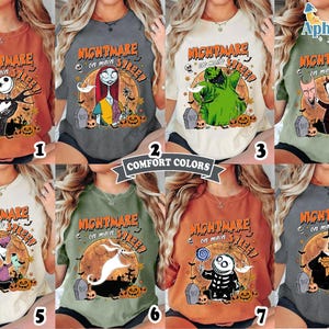 May include: A collection of eight short-sleeve t-shirts in various colors, each featuring a graphic print of a character from Nightmare on Main Street with a large orange moon, tombstones, and pumpkins. The text Nightmare on Main Street is printed above.