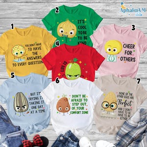a collection of seven t-shirts with various cartoon characters and motivational messages printed on them.