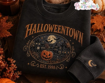 May include: A charcoal gray crewneck sweatshirt featuring an embroidered design with the text HALLOWEENTOWN and EST. 1998. The graphic depicts a spooky house, a large jack-o'-lantern, a full moon, and bats. A small crescent moon and bat are on the sleeve.