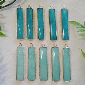 May include: Twelve turquoise blue gemstone bar pendants with gold-toned metal accents. Each pendant is approximately 1 inch long and has a faceted design.