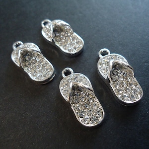 May include: Four silver flip-flop charms with clear rhinestone embellishments.