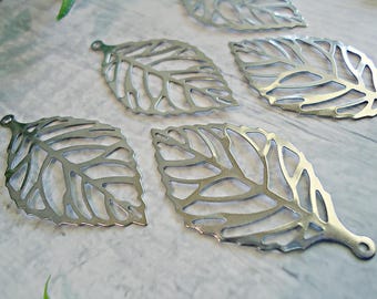May include: A collection of five silver-toned metal leaf charms, each featuring a detailed cut-out vein pattern and a small circular loop at the top for attachment. The charms have a smooth, reflective surface and a distinct botanical shape.
