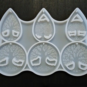May include: A white silicone mold with six cavities for making resin earrings. The mold features a tree of life design with a hole at the top for hanging.