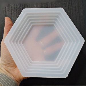 May include: A white hexagonal silicone mold with four concentric rings. The mold is designed for creating resin crafts.