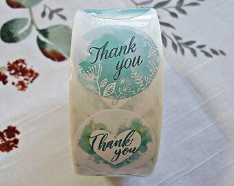 May include: Roll of round stickers with a watercolor design. The stickers are white with a teal blue and green watercolor design. The text "Thank you" is written in black cursive on each sticker.