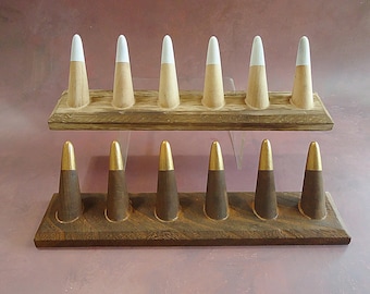 May include: Two wooden ring holders with a total of 12 ring cones. The top holder has 7 white-tipped cones and the bottom holder has 5 gold-tipped cones.