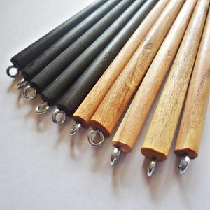 May include: A set of eight wooden dowels with metal rings at the end. The dowels are a mix of black and natural wood.