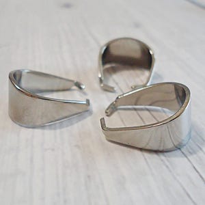 May include: Three silver-toned metal jewelry bails with a smooth, polished finish. Each piece features a U-shaped design with two small prongs extending inward at the open end, intended for attaching pendants to necklaces or other jewelry items.