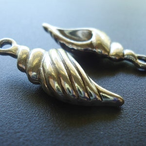 May include: Two silver seashell-shaped charms with a smooth, shiny finish. The charms have a detailed, textured design and are perfect for jewelry making.