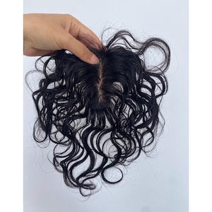 May include: A dark brown curly hair topper with a natural-looking scalp. The hair is styled in loose, flowing curls. The topper is designed to blend seamlessly with natural hair.