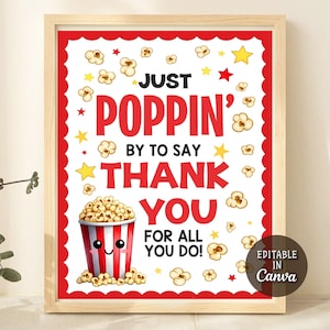 May include: A framed print with a red border and a white background. The print features the words "Just Poppin' by to say Thank You for all you do!" along with illustrations of popcorn and stars. A cartoon popcorn bucket is also included.