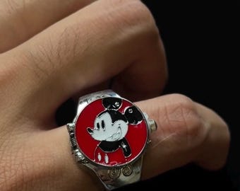 May include: Silver-toned ring featuring a red face with a smiling Mickey Mouse design. The ring has a detailed band with decorative elements. The Mickey Mouse image is in black, white, and red.
