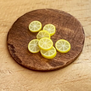 May include: A wooden cutting board with eight yellow lemon slices arranged in a circle.
