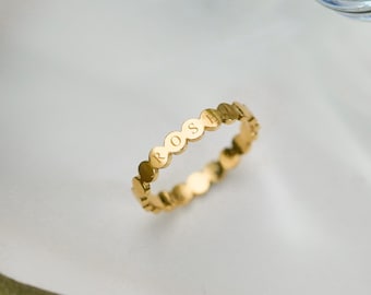 Könnte beinhalten: Ein goldfarbener Ring, der aus einer Reihe miteinander verbundener kreisförmiger Glieder besteht. Vier dieser Glieder sind mit den Buchstaben R, O, S und E graviert, die den Namen Rose in einer klaren Großschrift auf dem Ring bilden.