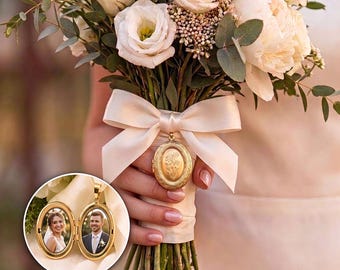 Könnte beinhalten: Ein Brautstrauß aus weißen Rosen, Pfingstrosen und Eukalyptuszweigen, gebunden mit einem cremefarbenen Satinband. Ein ovales, goldfarbenes Medaillon mit Blumengravur ist am Band befestigt. Ein Inset zeigt das geöffnete Medaillon mit zwei Porträtfotos.