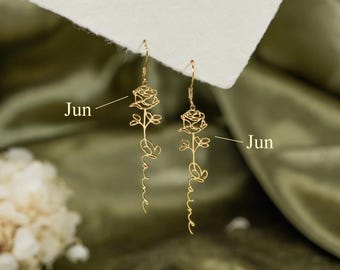 Könnte beinhalten: Ein Paar goldfarbene Ohrhänger mit einem linearen Design, das oben eine Rose und darunter den Namen Elaine in Schreibschrift zeigt. Der Text Jun ist neben jedem Ohrring zu sehen und weist auf eine individuelle Personalisierungsoption hin.