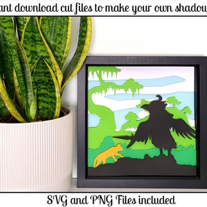 May include: A black framed shadow box with a layered paper cut design of a black bird and a yellow animal in a green and blue landscape. The text "SVG and PNG Files included" is below the frame.