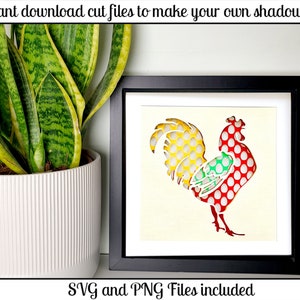 May include: A black frame with a white mat surrounding a red, yellow, and green rooster with white polka dots. The rooster is a cut-out design for a shadow box. The text "SVG and PNG Files included" is below the frame.