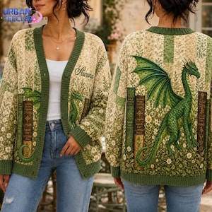 May include: A quilted cardigan featuring a green dragon and vintage book spine illustrations on a cream and green floral background. The front displays the name Aurora in script, while the back showcases a large green dragon with wings.