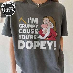 May include: Dark gray t-shirt with the text "I'M GRUMPY CAUSE YOU'RE DOPEY!" and a cartoon image of Grumpy from Snow White. The shirt also has a pickaxe graphic and the words "COMFORT COLORS" and "PEPPER" in a circle.