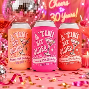 May include: Three colorful can coolers with the text "A'Tini Bit Older" and "Emma's 30th Birthday EST. 1996". The coolers are in shades of orange, pink, and red, with a martini glass graphic. The background includes a disco ball and the words "Cheers to 30 Years!"
