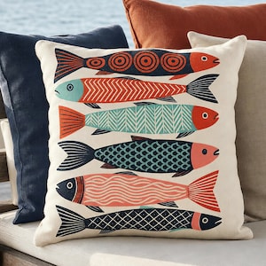 Könnte beinhalten: Ein quadratisches Dekokissen mit cremefarbenem Hintergrund und einer vertikalen Anordnung von sechs stilisierten Fischillustrationen. Die Fische sind in verschiedenen Farben wie Marineblau, Orange, Türkis und Lachs gehalten und haben geometrische Muster.