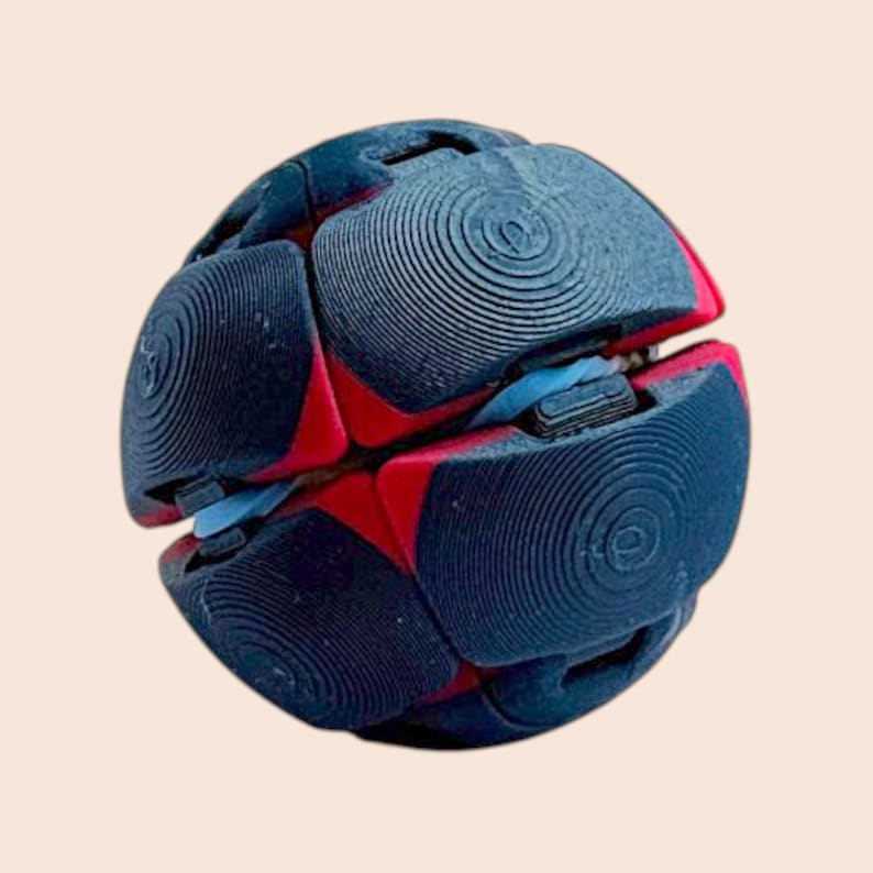 Pu&ograve; includere: Un giocattolo puzzle sferico con un design complesso. Il giocattolo &egrave; principalmente blu navy con accenti rossi e azzurri. Ogni sezione della sfera presenta un motivo circolare. Il giocattolo &egrave; progettato per essere manipolato e risolto.