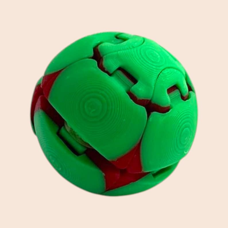 Pu&ograve; includere: Una palla puzzle verde e rossa. La palla &egrave; composta da diversi pezzi ad incastro, con pannelli esterni verdi e accenti rossi. I pezzi si incastrano per formare una forma sferica. La superficie dei pannelli verdi ha un aspetto strutturato.