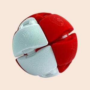 Pu&ograve; includere: Un giocattolo puzzle a forma di palla rossa e bianca. Il giocattolo &egrave; composto da pezzi ad incastro, con segmenti rossi e bianchi alternati. I segmenti bianchi hanno un motivo circolare. Il giocattolo &egrave; progettato per essere manipolato e risolto.